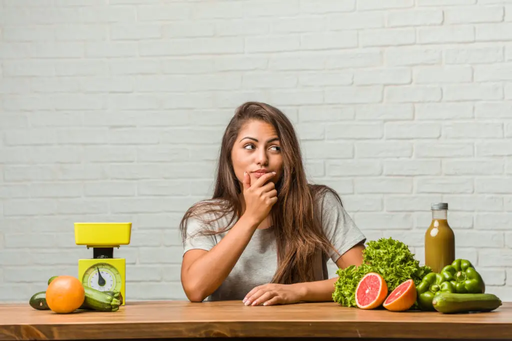 Concept of diet. Portrait of a healthy young latin woman doubting and confused thinking of an idea or worried about something